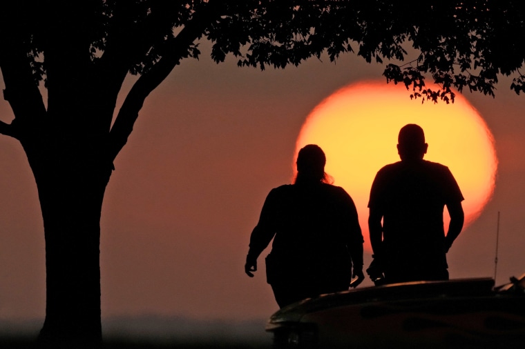 A couple watches the sunset as triple-digit heat indexes continue in the Midwest Sunday, Aug. 20, 2023, in Kansas City, Mo.