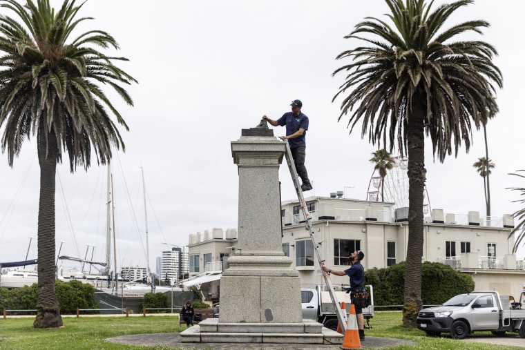 Workers remove the remnants of a Captain Cook statue in Melbourne on Thursday after vandals cut the statue off at the ankles.